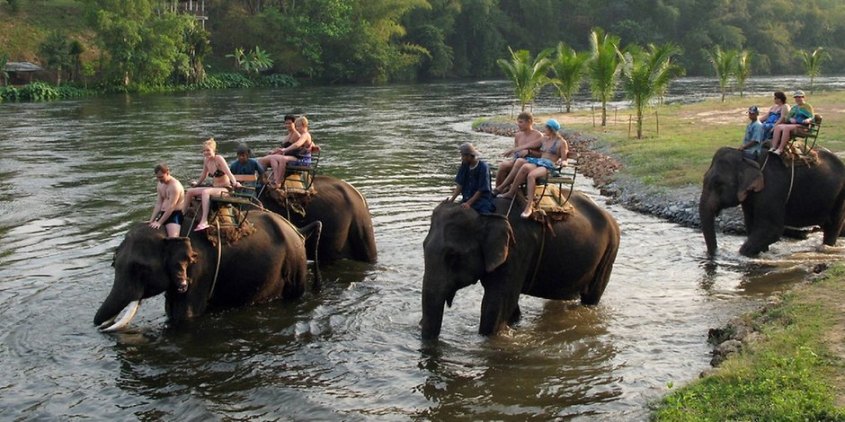 touristen-reiten-auf-elefant-durchs-wasser